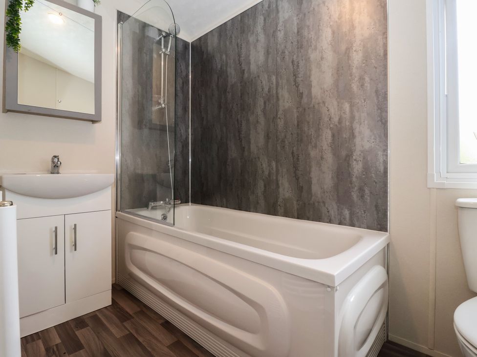 A bathroom with a bathtub, sink, mirror, and toilet at Meadows Park 3 in Great Hatfield near Hornsea