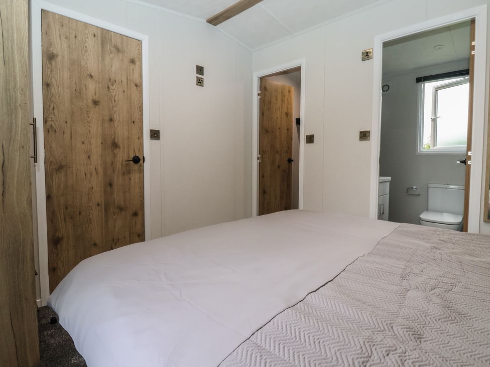 A bedroom with a bed and doors leading to a bathroom at Meadows Park 3 near Hornsea