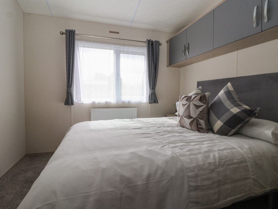 A bedroom with a bed and window at Meadows Park 4 Great Hatfield near Hornsea