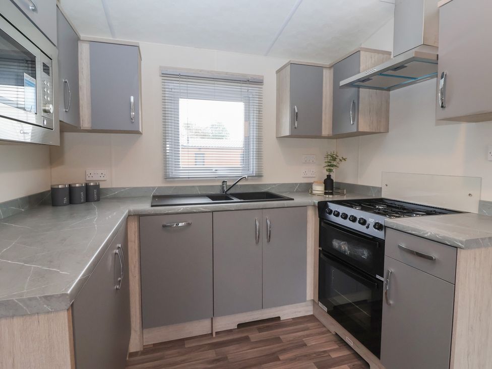 A kitchen featuring a sink, cooker, and microwave at Meadows Park 4 Great Hatfield near Hornsea