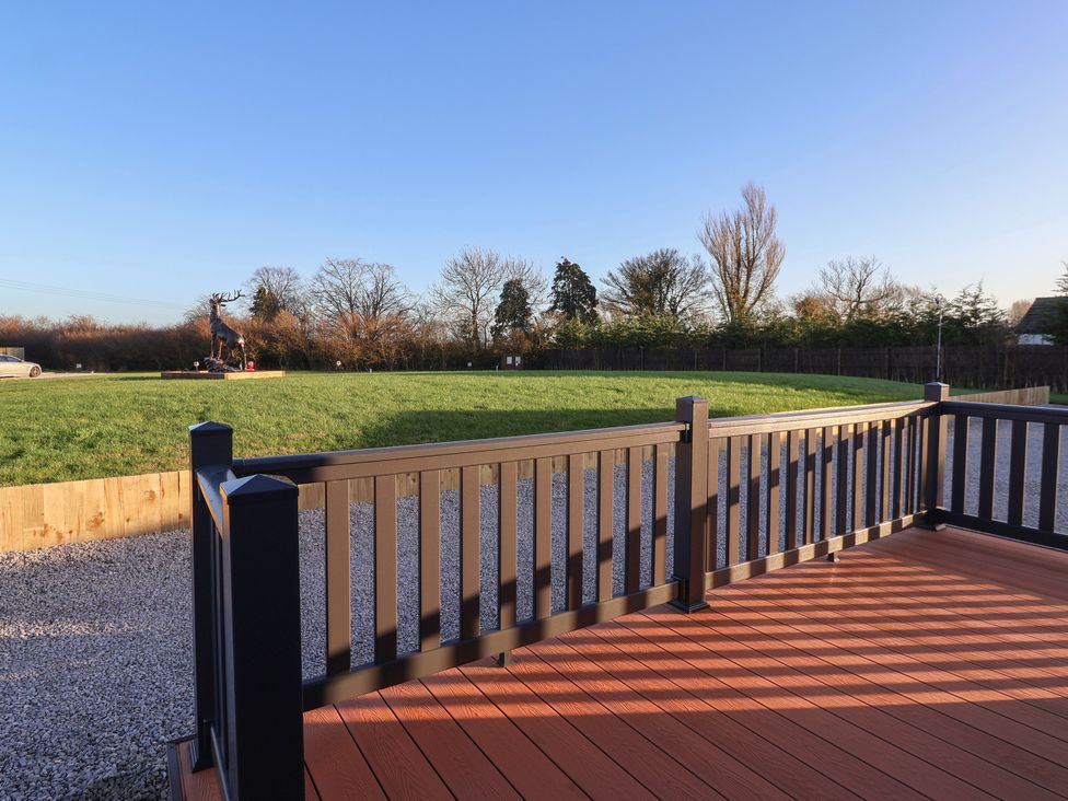 A deck overlooking a grassy area with trees and a sculpture at Meadows Park 4 Great Hatfield near Hornsea