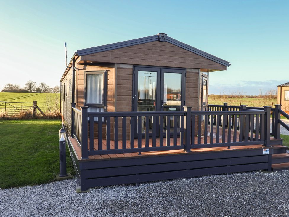 A cabin exterior with a deck and railing at Meadows Park 5 Great Hatfield near Hornsea