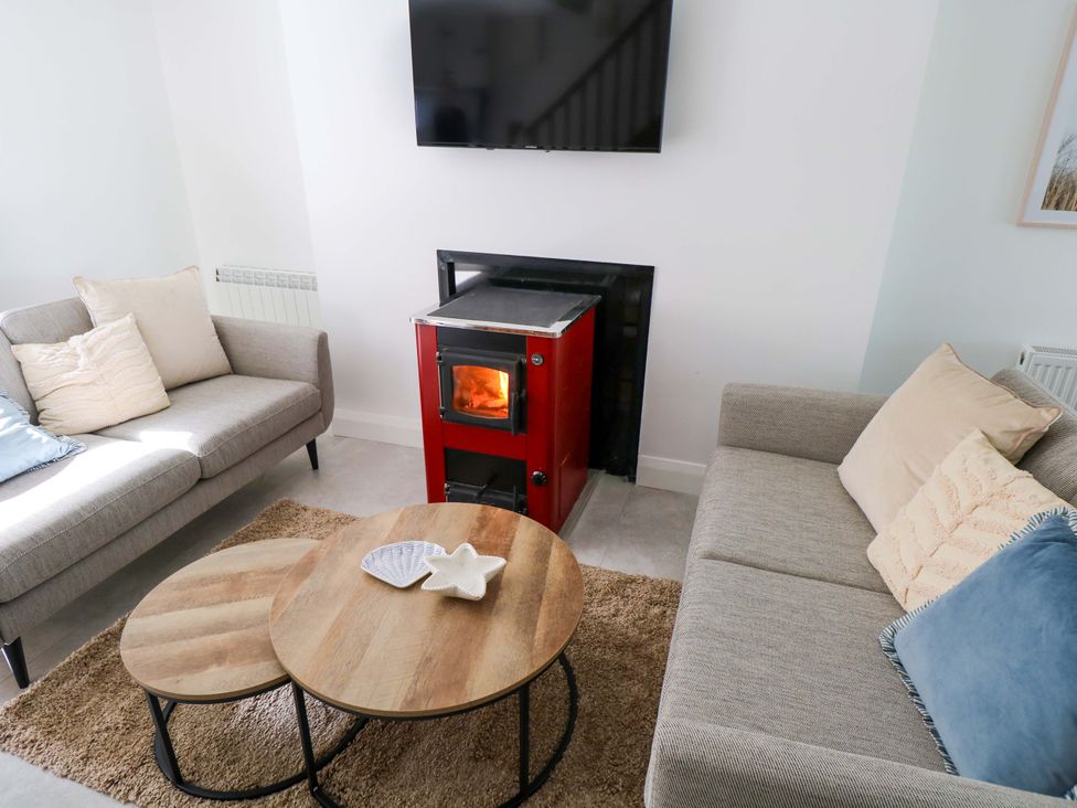 A living room with a stove and two sofas at Rose Cottage in Killala, County Mayo