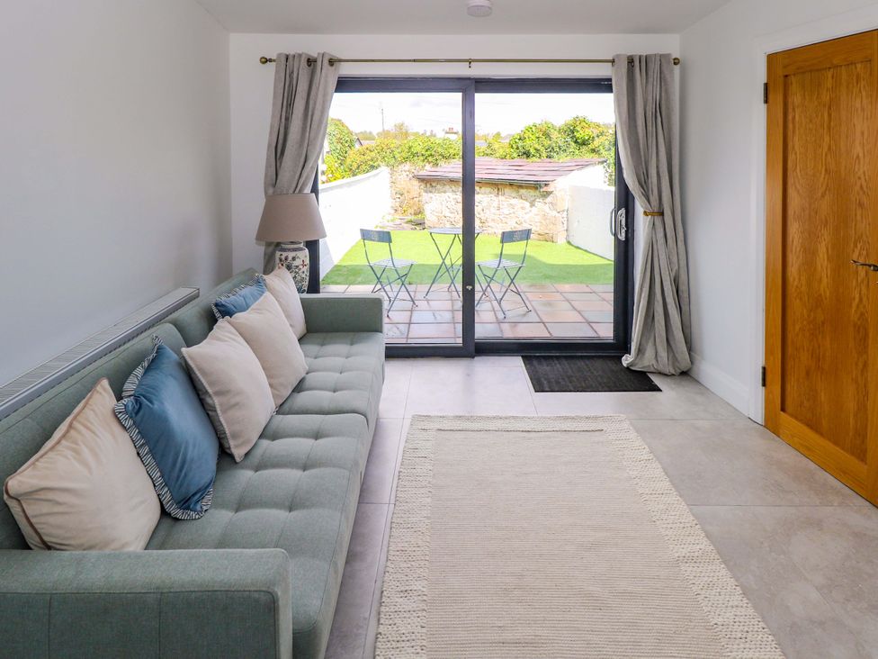 A living room with a sofa and sliding glass door at Rose Cottage, Killala, County Mayo
