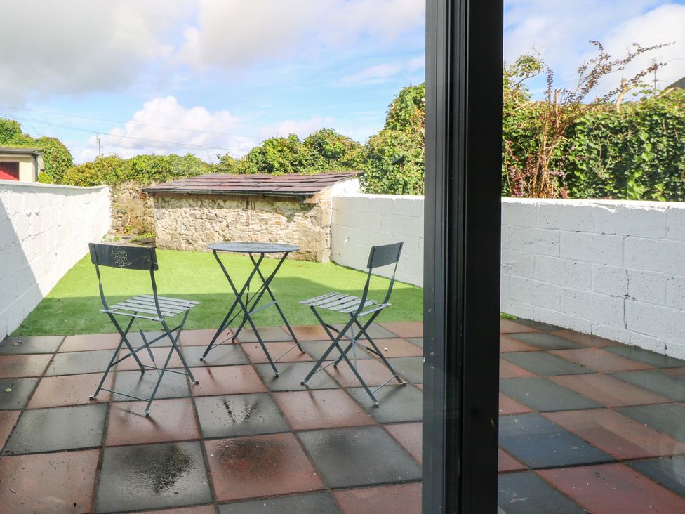 An outdoor patio with a table and three chairs at Rose Cottage in Killala, County Mayo