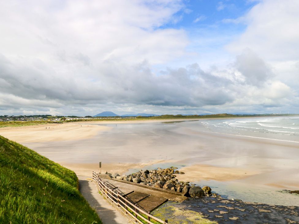 A beach with sand and ocean under a cloudy sky at Rose Cottage in Killala, County Mayo
