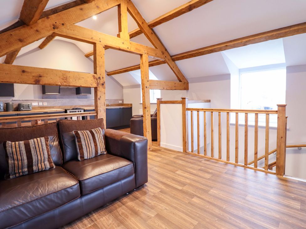 A living room with a sofa and kitchen area at Clegir Bach in Corwen