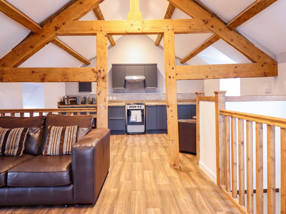 A living room with a sofa and kitchen area at Clegir Bach in Corwen