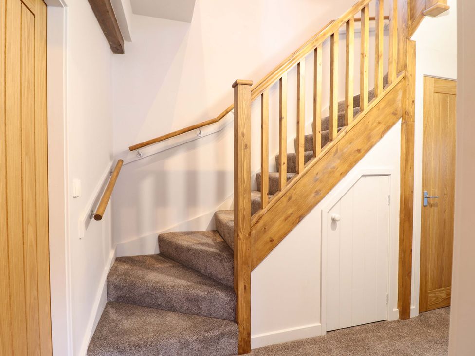 A staircase with wooden railings and carpet at Clegir Bach in Corwen