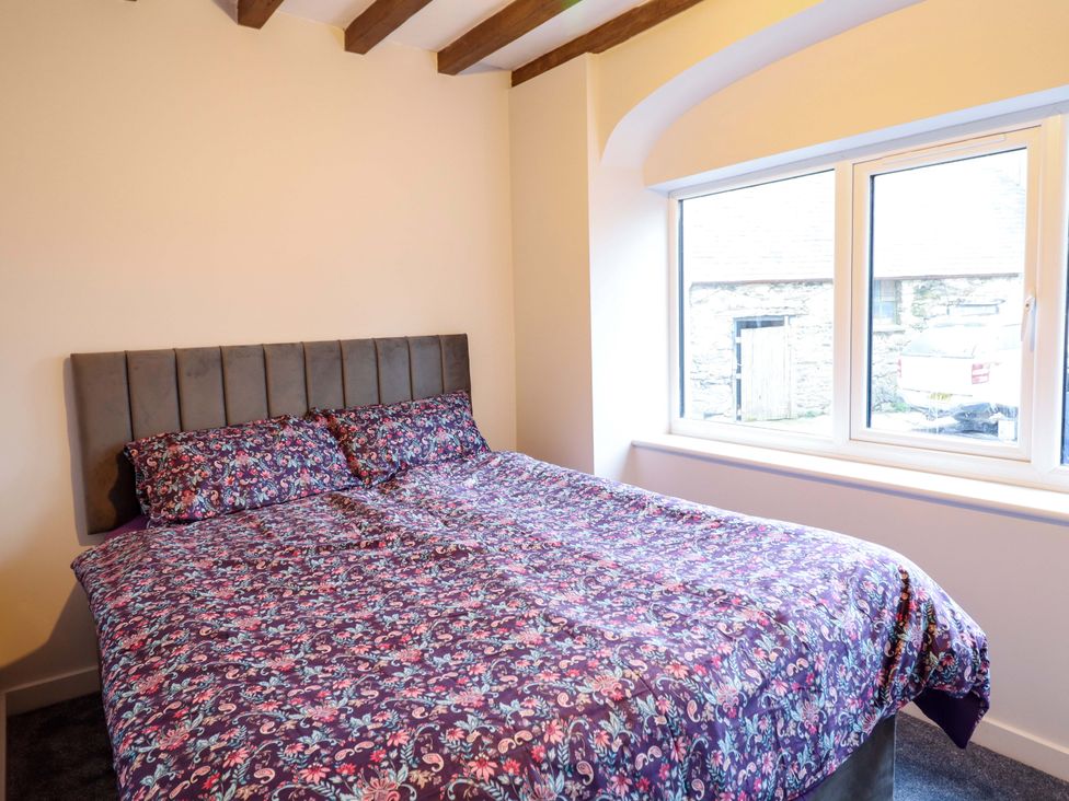 A bedroom with a bed and window at Clegir Bach in Corwen