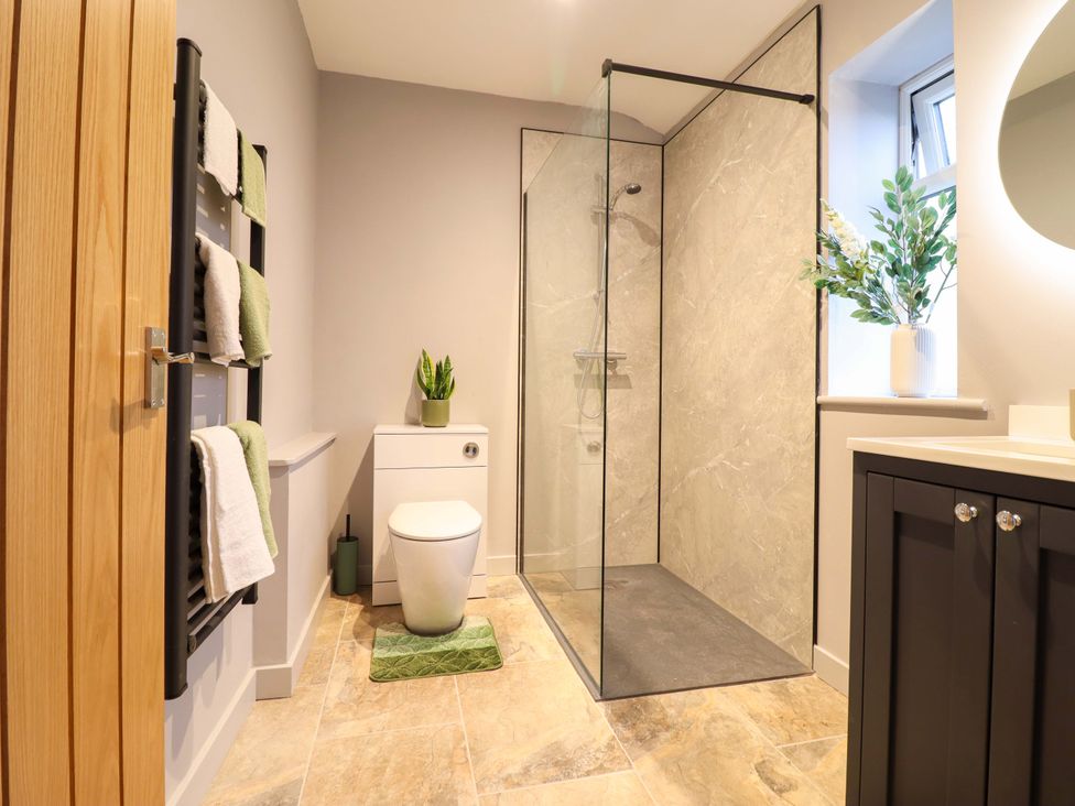 A bathroom featuring a shower, toilet, sink and towels at Clegir Bach Corwen