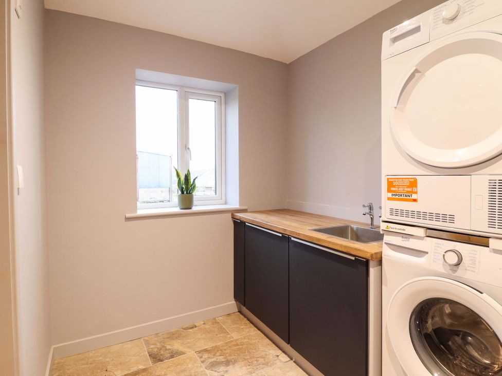 A laundry room with a sink and washer dryer at Clegir Bach in Corwen