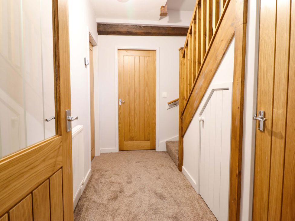 A hallway with staircase and wooden doors at Clegir Bach Corwen