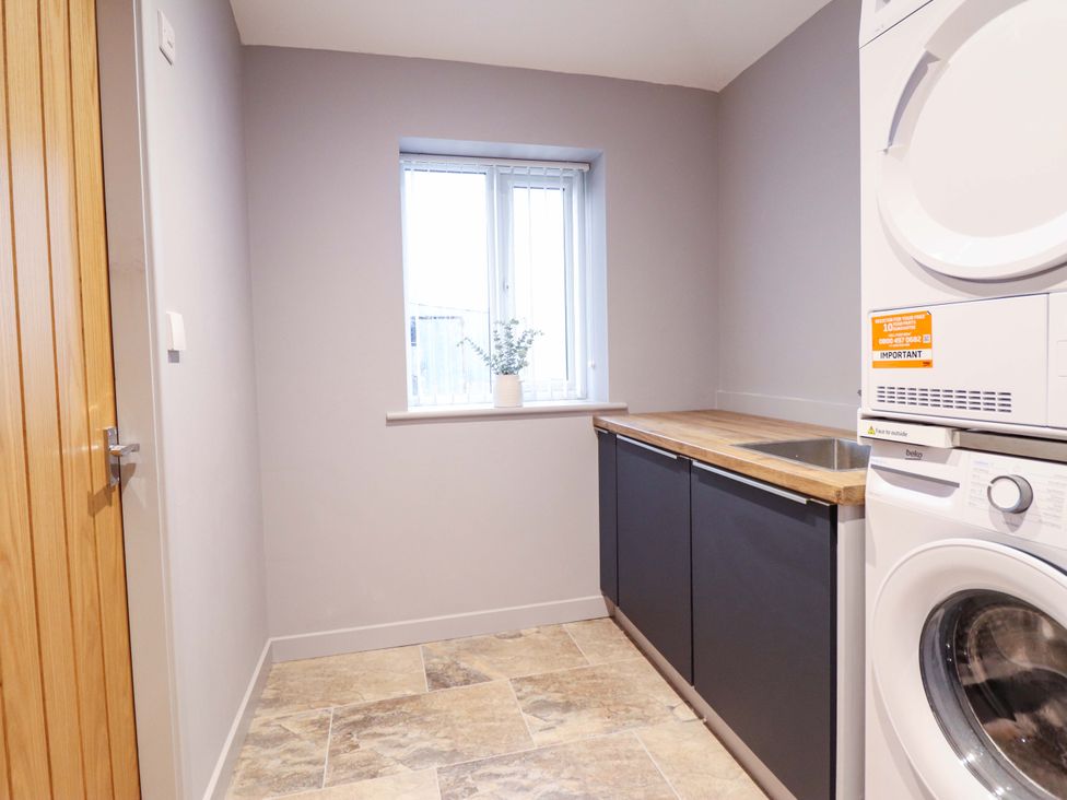 A laundry room with a washer and dryer and a countertop at Clegir Bach Betws Gwerfil Goch near Corwen