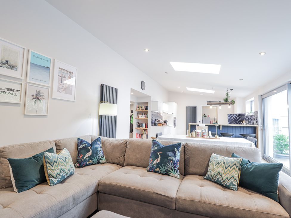 A living room with a sofa and kitchen area at Apple Tree Cottage in Cullen
