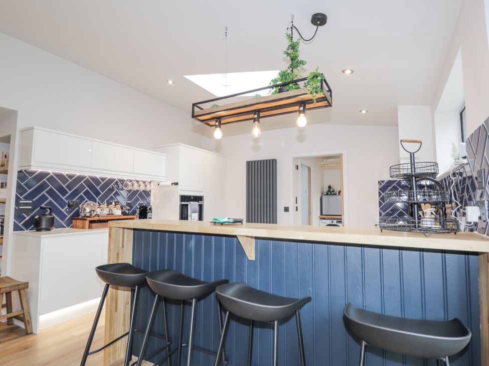 A kitchen with bar stools and cabinets at Apple Tree Cottage in Cullen