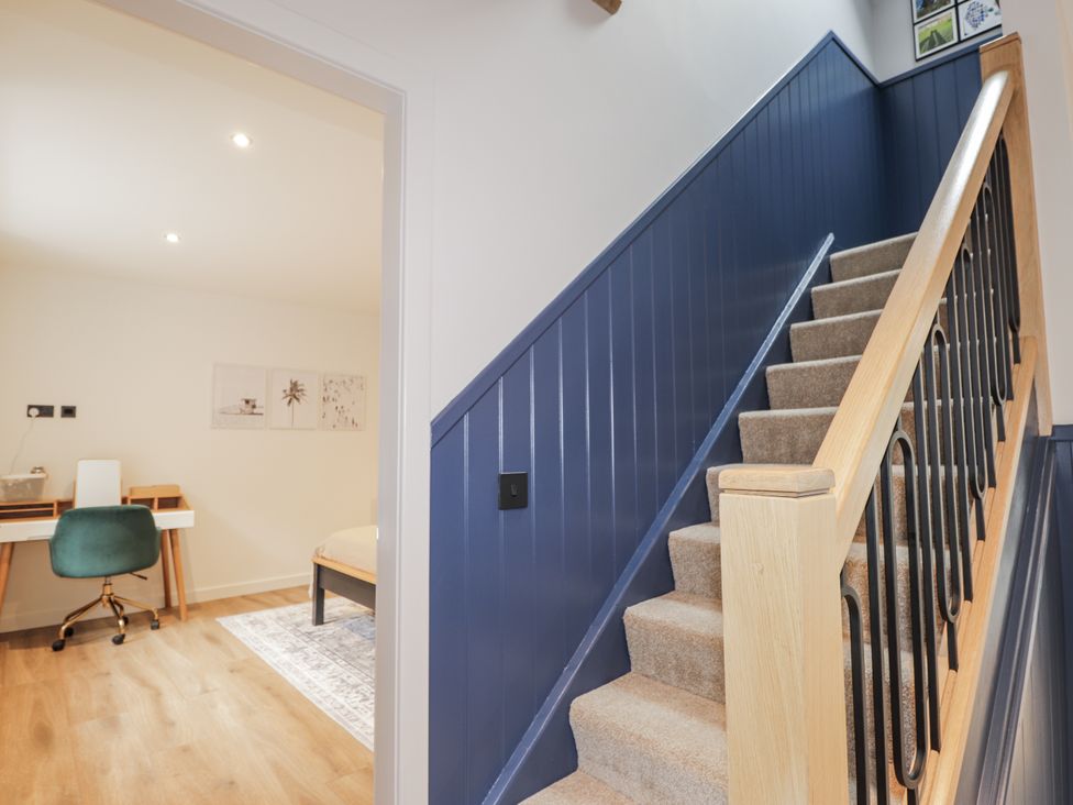 A staircase with a handrail leading to a room with a desk at Apple Tree Cottage in Cullen