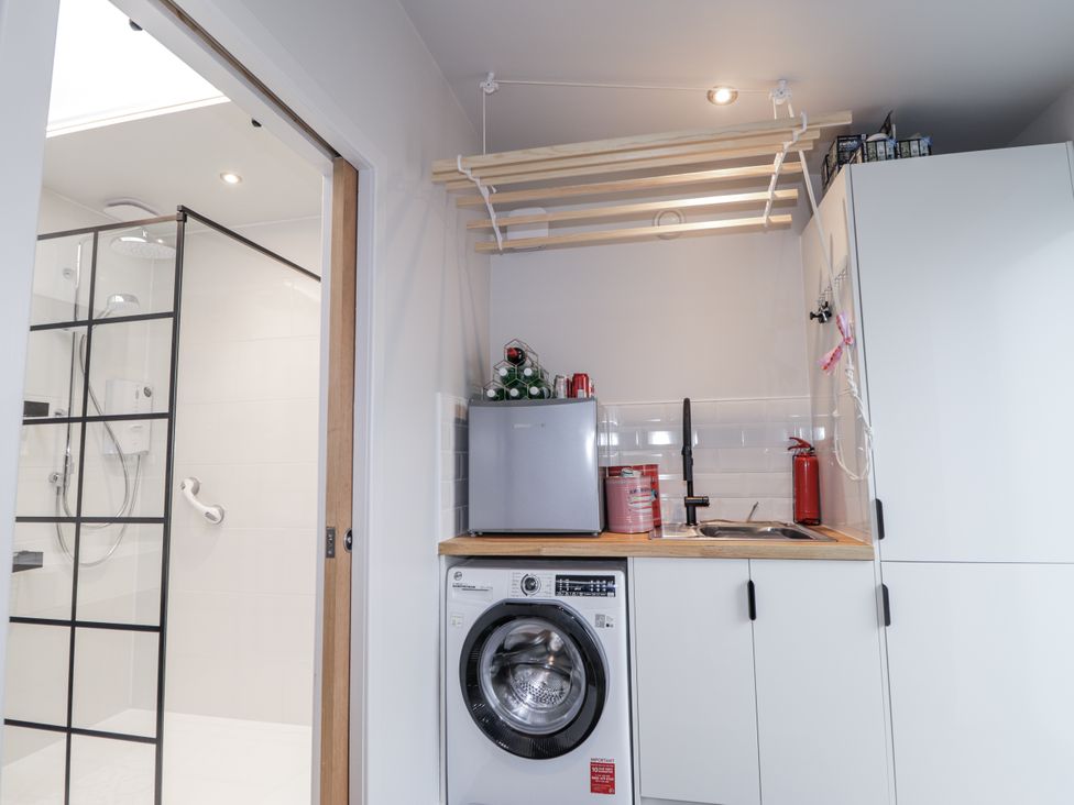 A laundry room featuring a washing machine, sink, and mini fridge at Apple Tree Cottage in Cullen