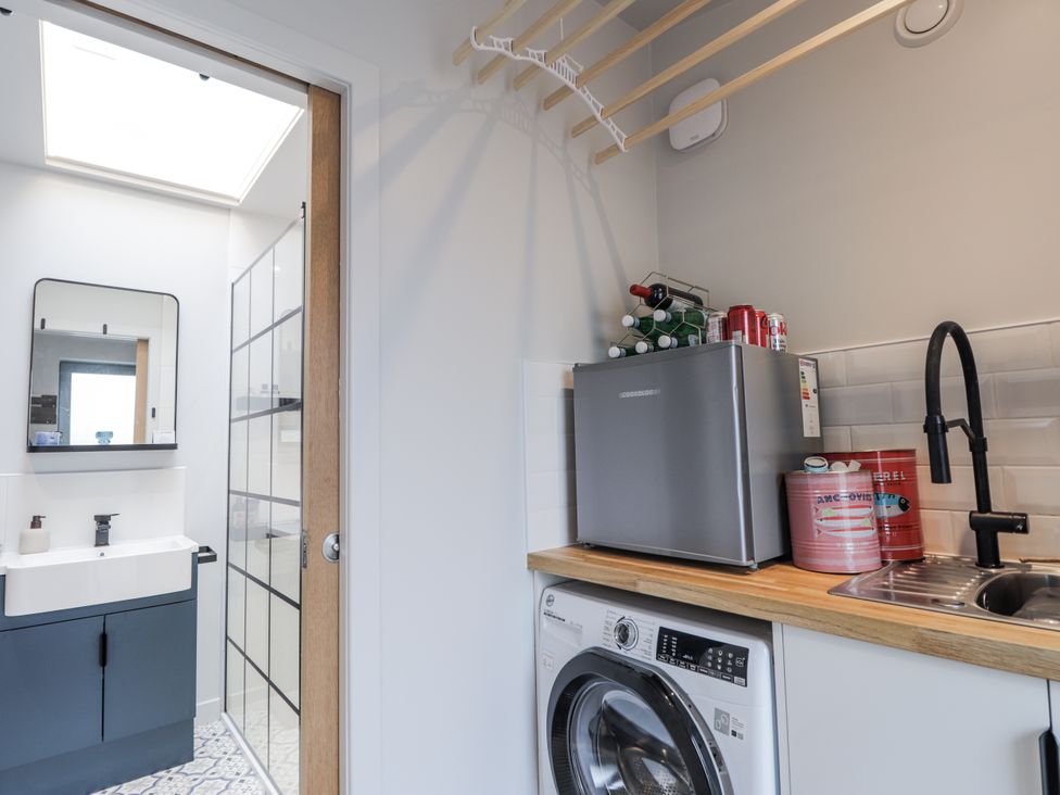 A bathroom with a washing machine and mini fridge at Apple Tree Cottage Cullen