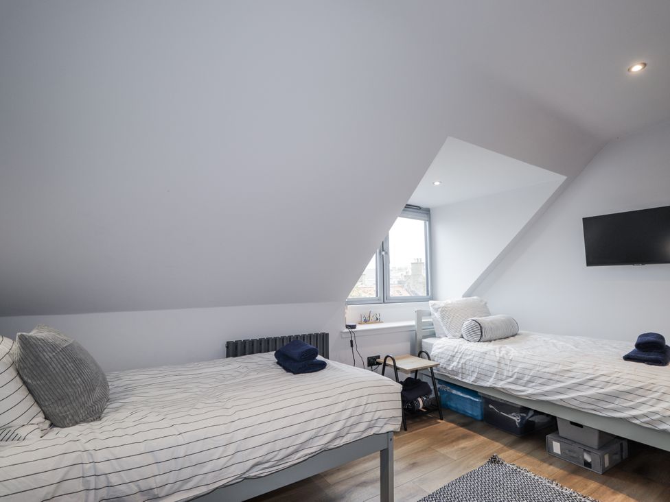 A bedroom with two beds and a television at Apple Tree Cottage in Cullen