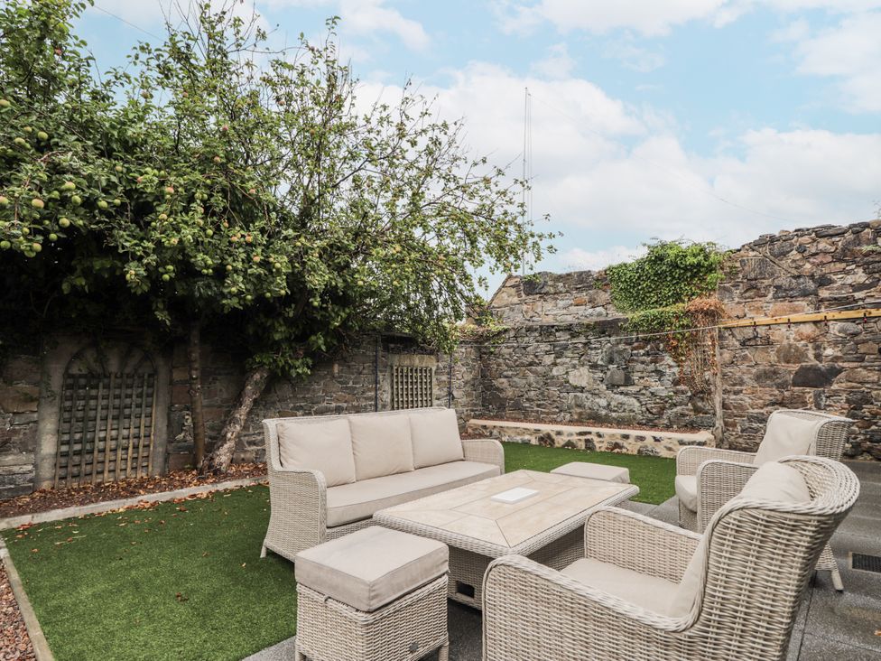 A garden with outdoor seating and a stone wall at Apple Tree Cottage in Cullen