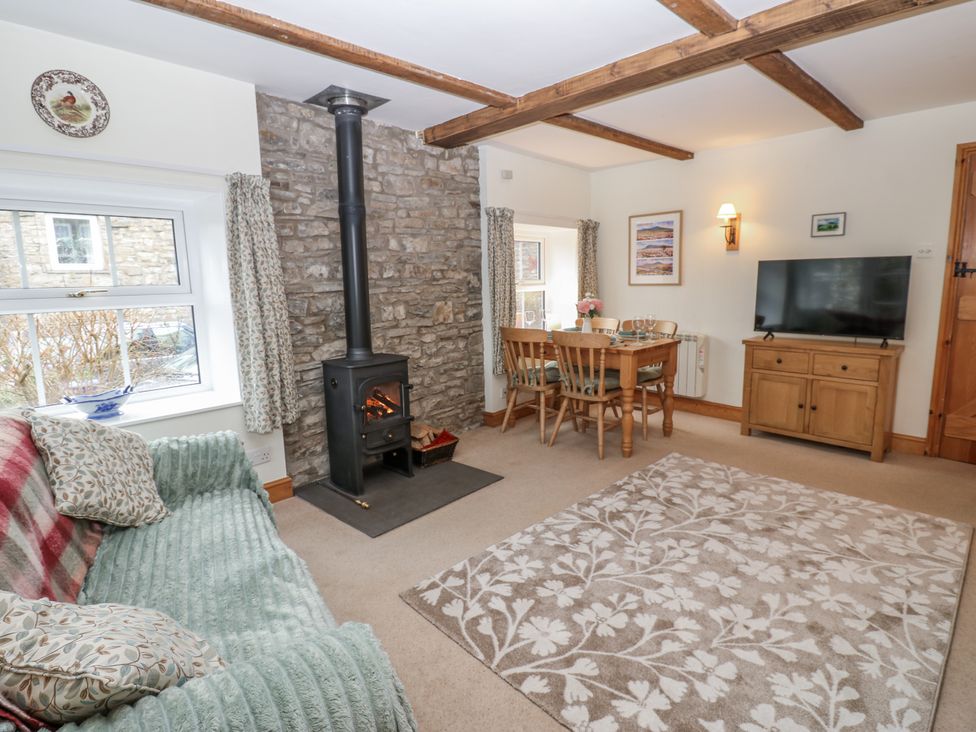 A living room with a fireplace and dining table at 1 Mill Cottage near Askrigg