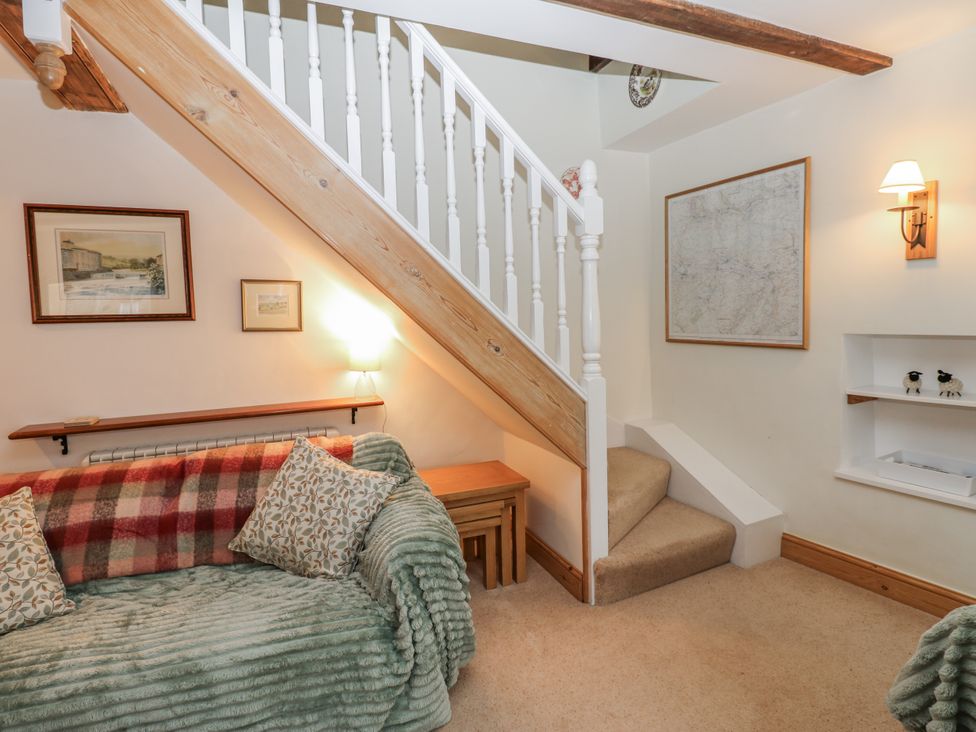 A living room with a sofa and staircase at 1 Mill Cottage (known as Old Mill 1) Askrigg near West Burton