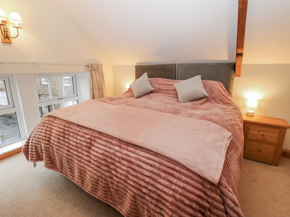 A bedroom with a bed and windows at 1 Mill Cottage (known as Old Mill 1) Askrigg near West Burton