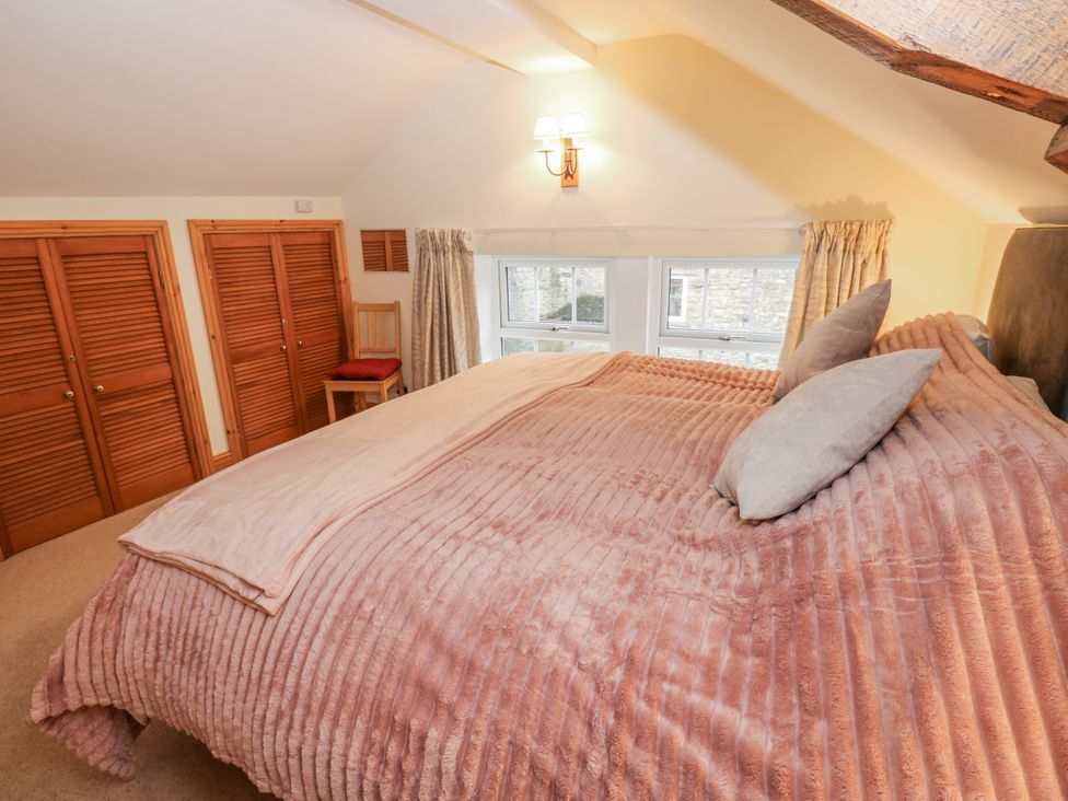 A bedroom with a bed and windows at 1 Mill Cottage (known as Old Mill 1) Askrigg near West Burton