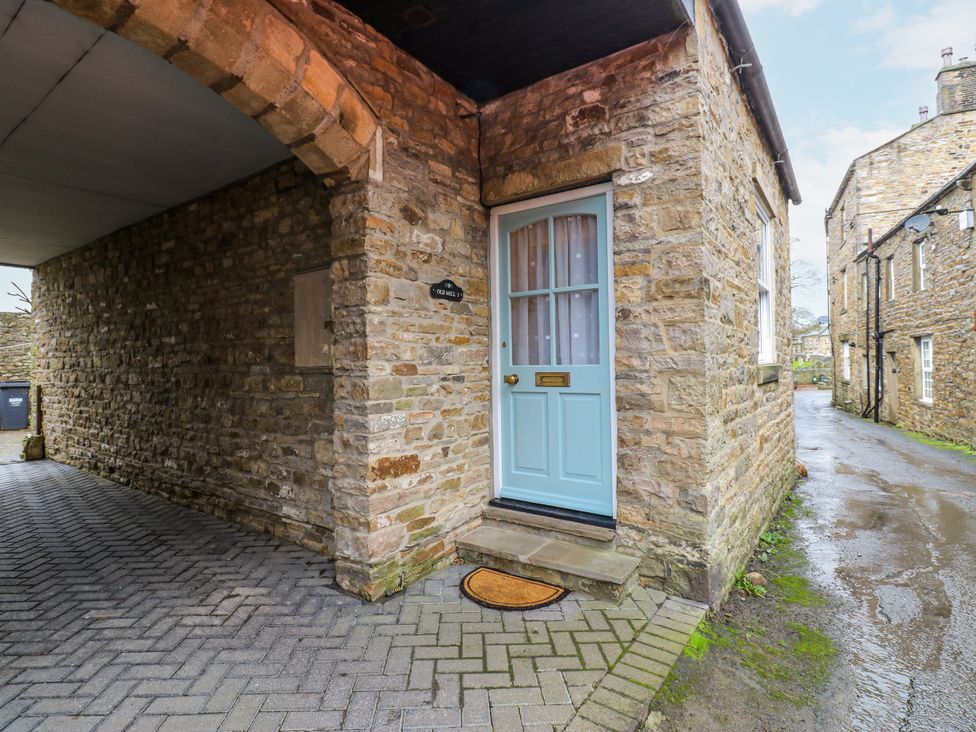 A front entrance with a blue door and stone walls at 1 Mill Cottage in Askrigg near West Burton