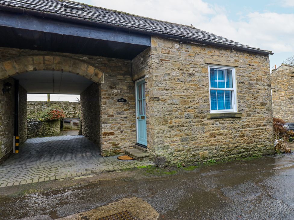 A stone building with a blue door and window at 1 Mill Cottage near West Burton