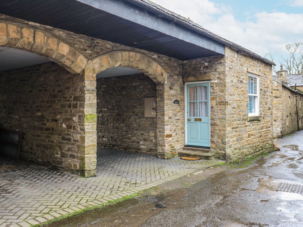 An outdoor photo of a stone building with a blue door at 1 Mill Cottage (known as Old Mill 1) Askrigg near West Burton