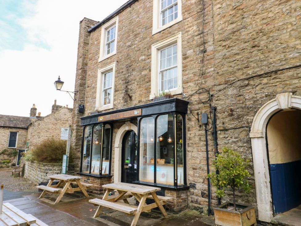 A building exterior with tables and benches at 1 Mill Cottage (known as Old Mill 1) in Askrigg near West Burton