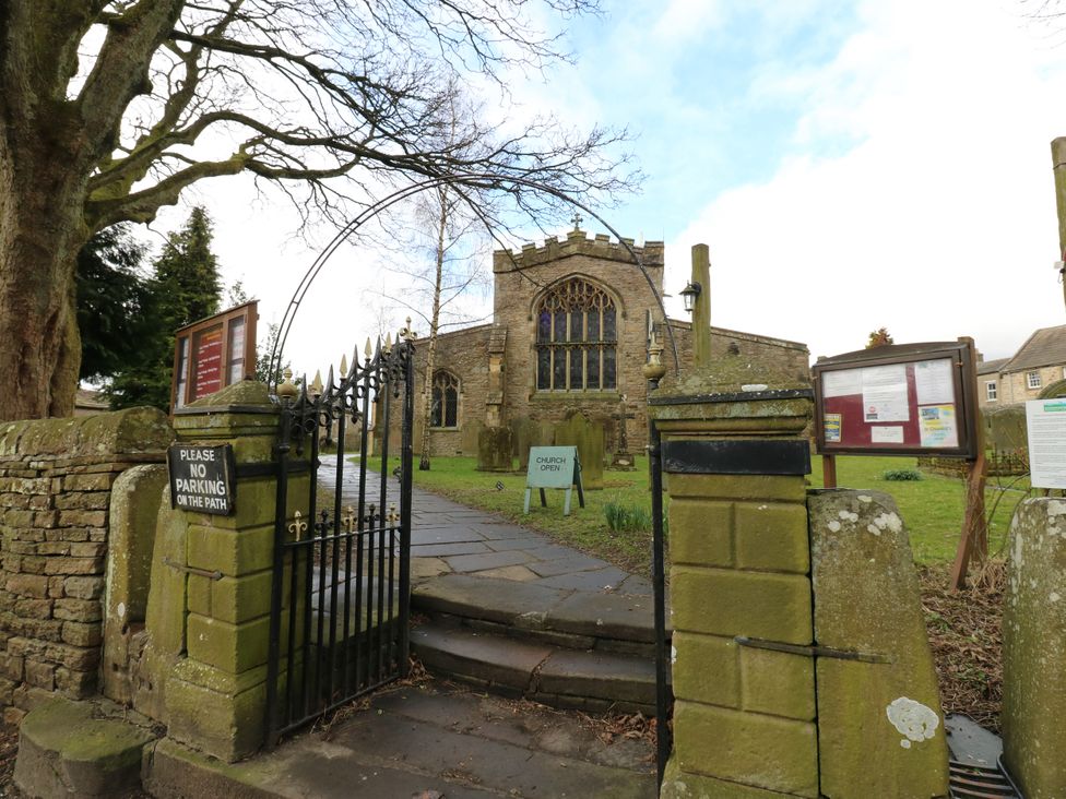 An outdoor view of a church with a gate and path at 1 Mill Cottage in Askrigg near West Burton