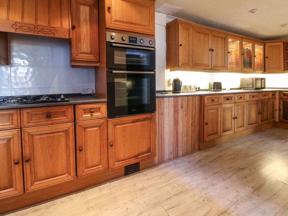 A kitchen with wooden cabinets and appliances at Mariners Lee