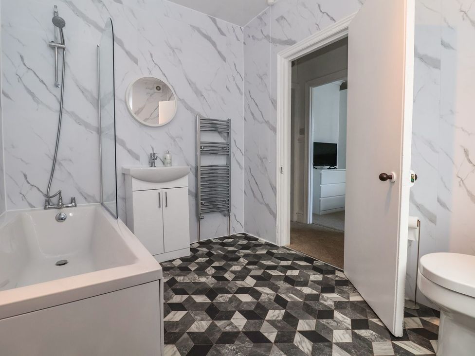 A bathroom with a bathtub, sink, and towel rack at Mariners Lee 