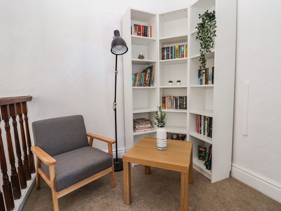 A reading nook with a chair, table, and bookshelf at Mariners Lee in 
