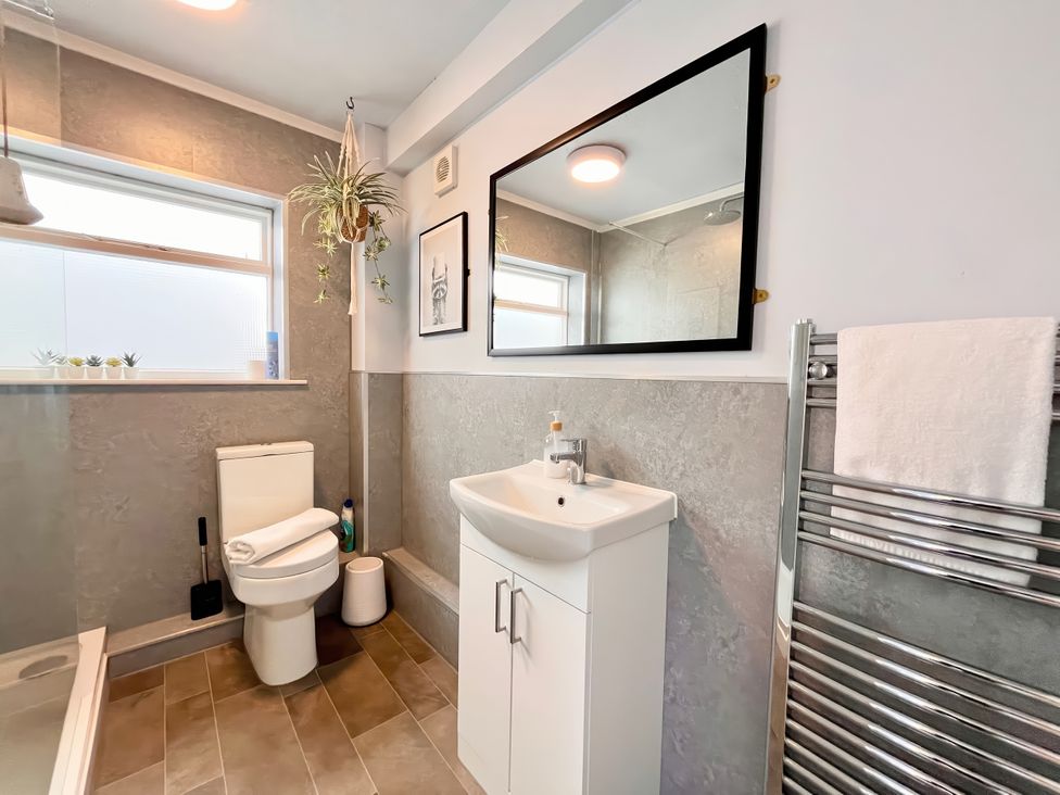A bathroom with a toilet, vanity, and mirror at Clarence House in Llandudno