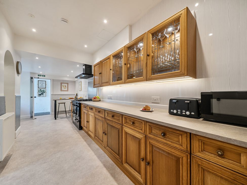 A kitchen with wooden cabinets and appliances at Clarence House in Llandudno