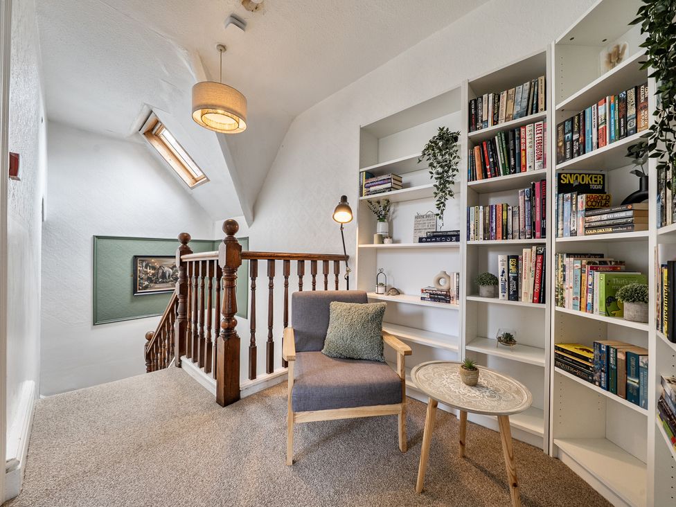 A hallway with a staircase and bookshelves at Clarence House in Llandudno