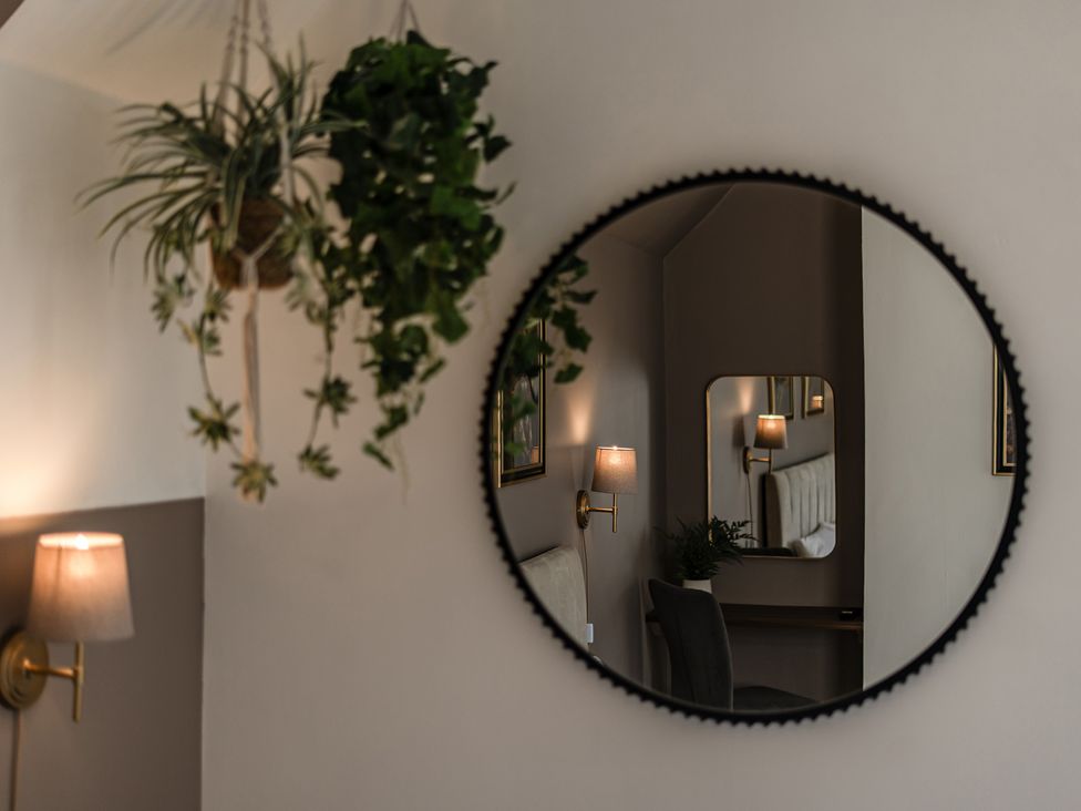 A living room with a mirror and hanging plants at Clarence House in Llandudno