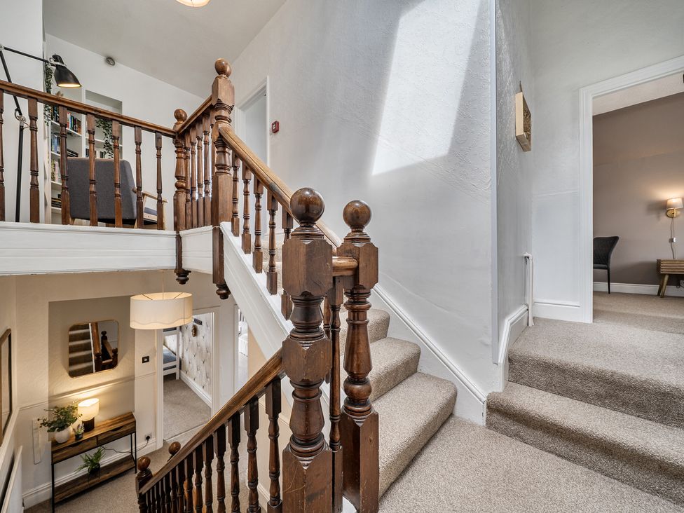 A hallway with stairs and a bookshelf at Clarence House in Llandudno