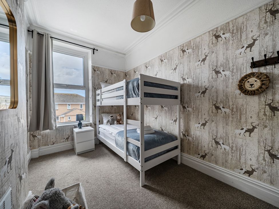 A bedroom with a bunk bed and a bedside table at Clarence House in Llandudno