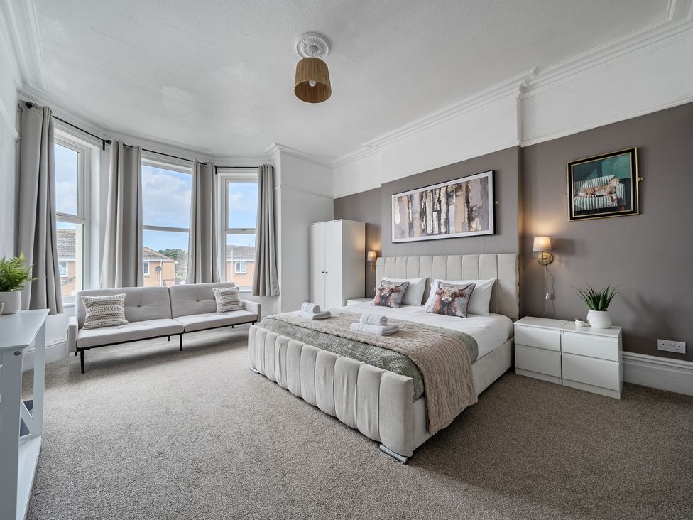 A bedroom with a bed and a sofa at Clarence House in Llandudno