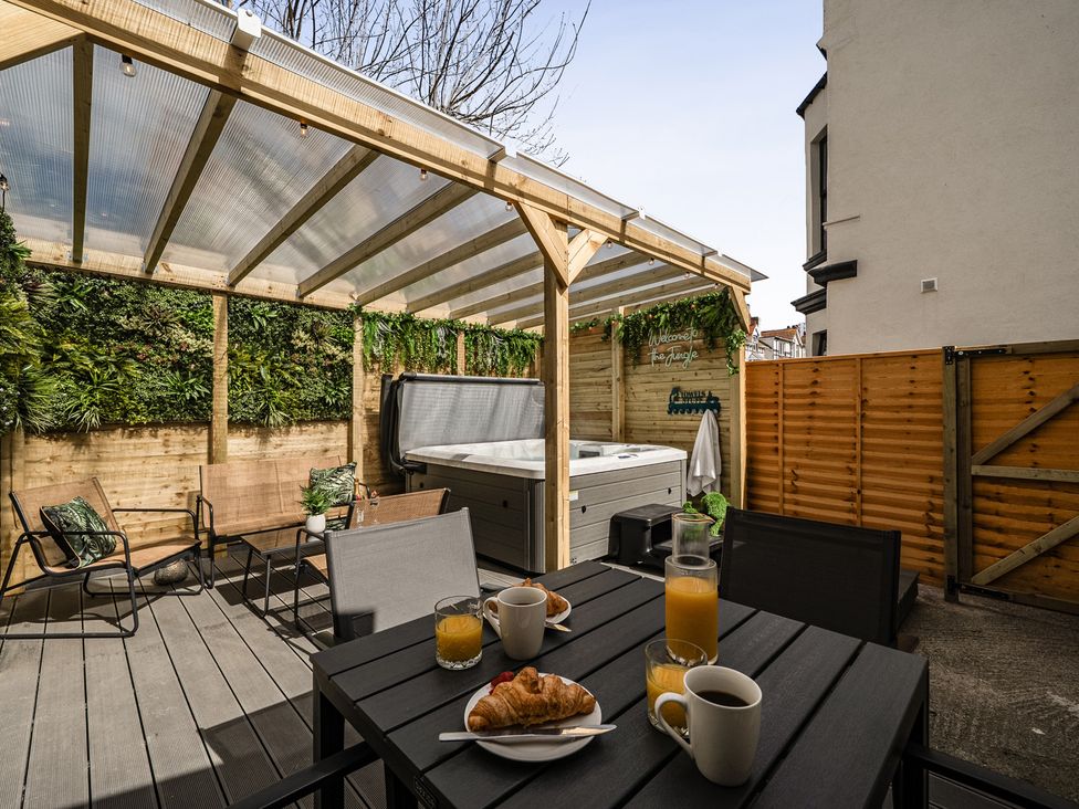 An outdoor seating area with a hot tub and breakfast items at Clarence House in Llandudno