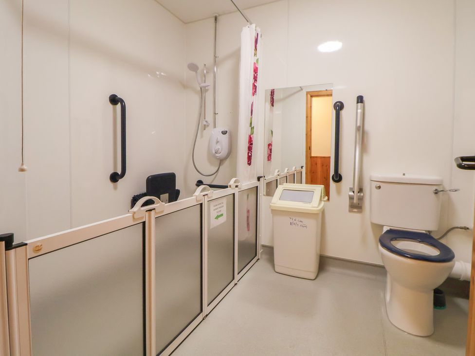 A bathroom with a shower, toilet, and grab bars at Clwyd Special Riding Centre