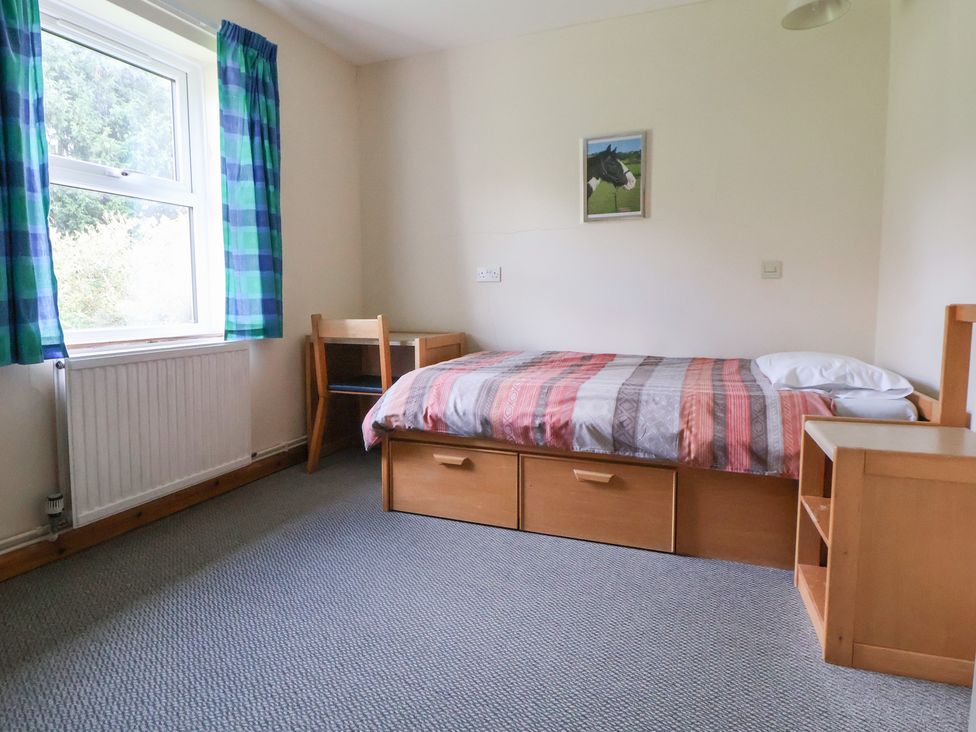 A bedroom with a bed and chair at Clwyd Special Riding Centre