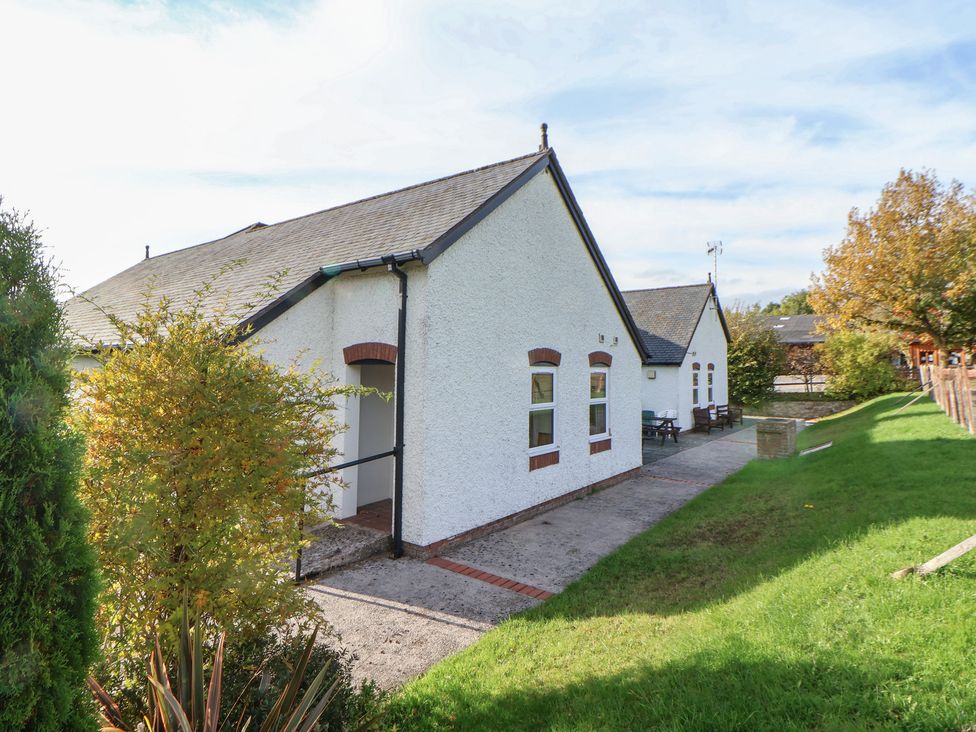 A building exterior with pathway and seating area at Clwyd Special Riding Centre