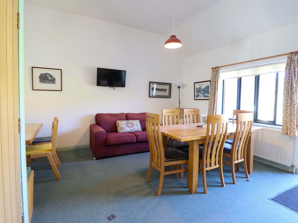 A dining room with a table and chairs beside a sofa at Clwyd Special Riding Centre in Llanfynydd