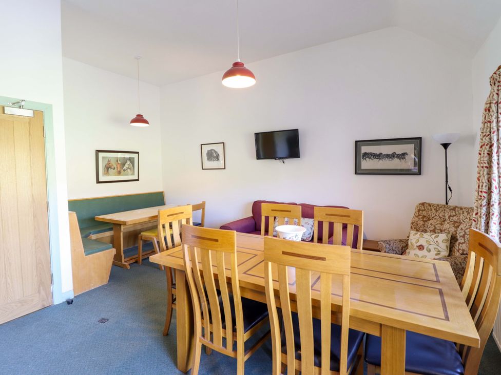 A dining room with a wooden table and chairs at Clwyd Special Riding Centre in Llanfynydd